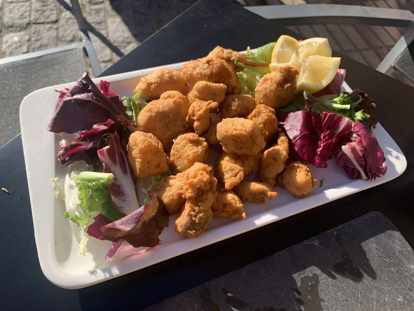 Bocados de pollo frito crujiente con ensalada fresca y limón