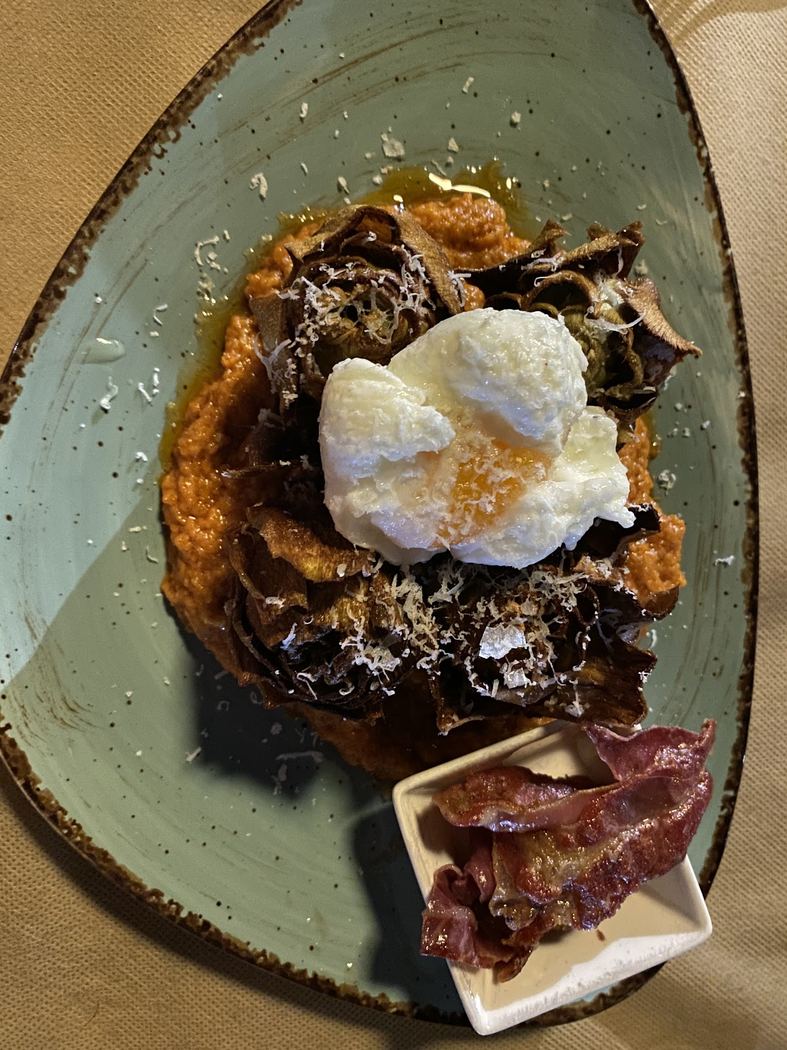 Alcachofas confitadas con huevo poché, salsa romesco y bacon